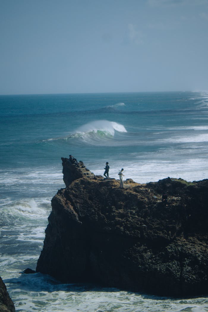 Two people stand on a dramatic cliff overlooking the ocean at Tasikmalaya, Indonesia.